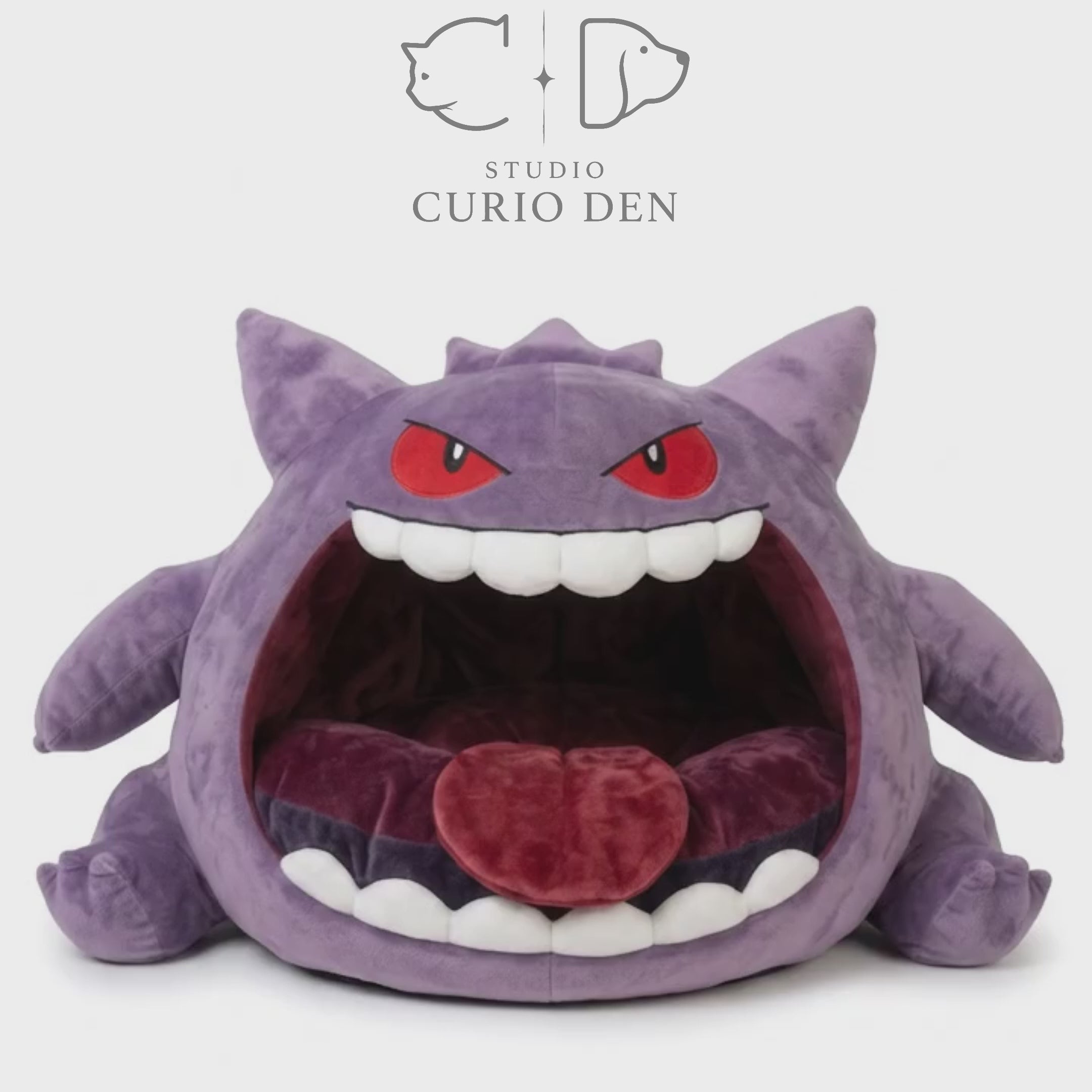 Purple monster cave pet bed with an open mouth design, white felt teeth, and soft red cushion.